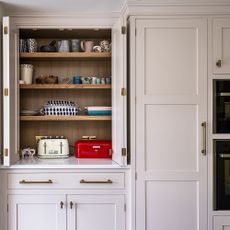 Pink shaker kitchen with pantry filled with small appliances.