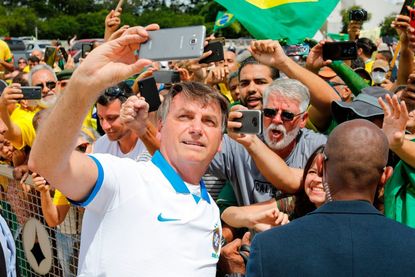 Brazilian President Jair Bolsonaro takes selfies with supporters.