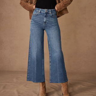 A model wears some faded blue cropped wide leg jeans with suede boots