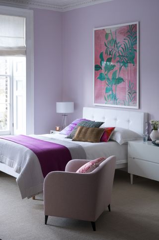 Lilac bedroom with artwork, white bed linen and colorful cushions