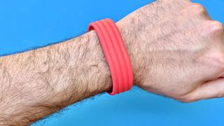 Close-up of the Fitbit Air on-wrist on a red strap against a blue background