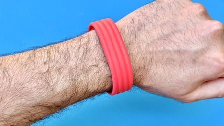 Close-up of the Fitbit Air on-wrist on a red strap against a blue background