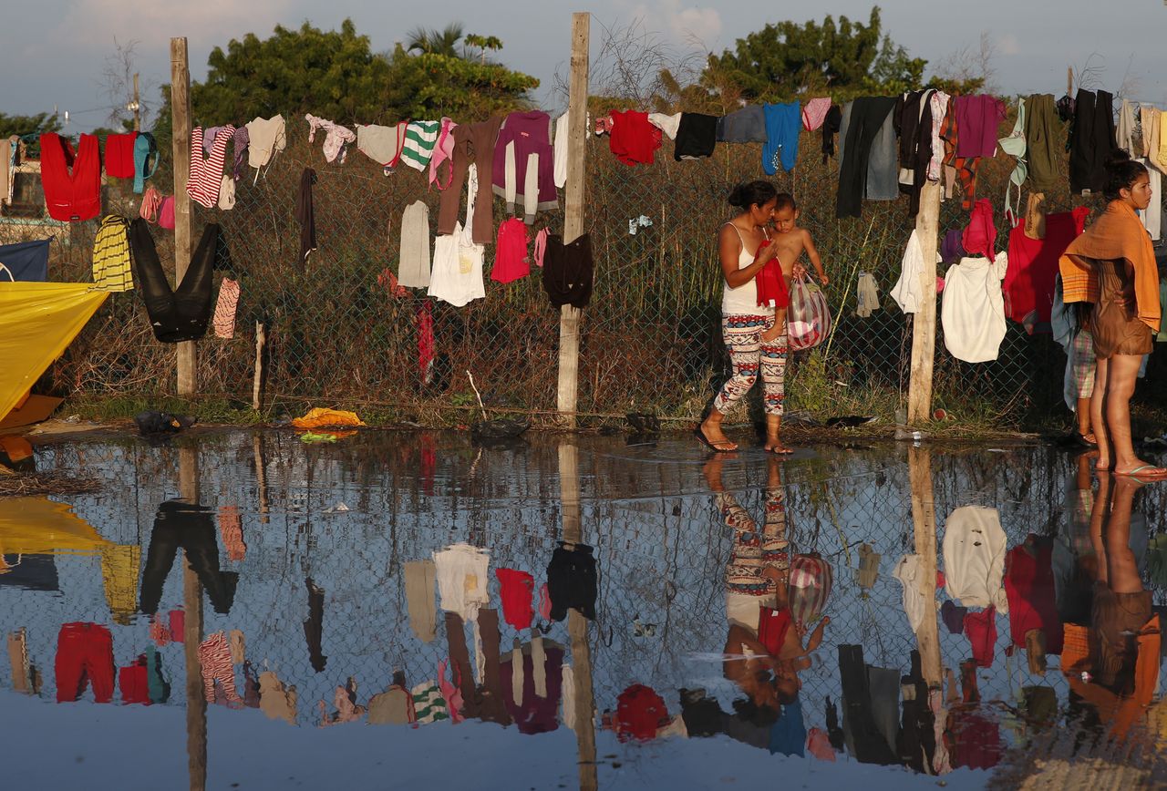 A woman fetches her dried clothes as a caravan of Central Americans hoping to reach the U.S. border takes a rest day in Juchitan, Oaxaca state, Mexico.