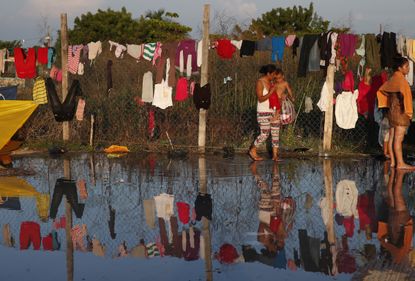 A woman fetches her dried clothes as a caravan of Central Americans hoping to reach the U.S. border takes a rest day in Juchitan, Oaxaca state, Mexico.