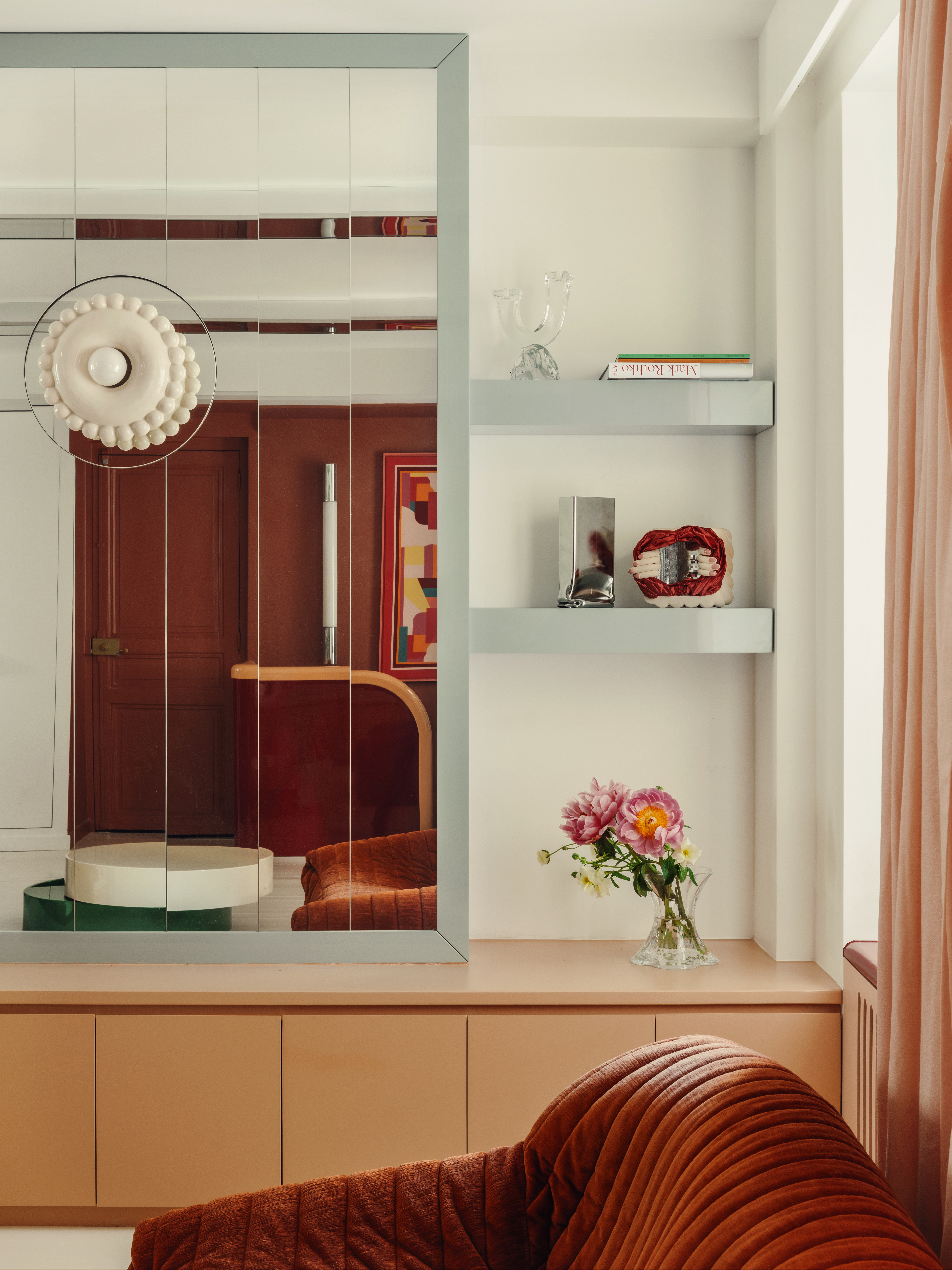 A close-up of the living room wall, which features a mirrored expanse that reflects the colorful interior.
