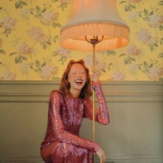Women in pink dress holding on to lamp