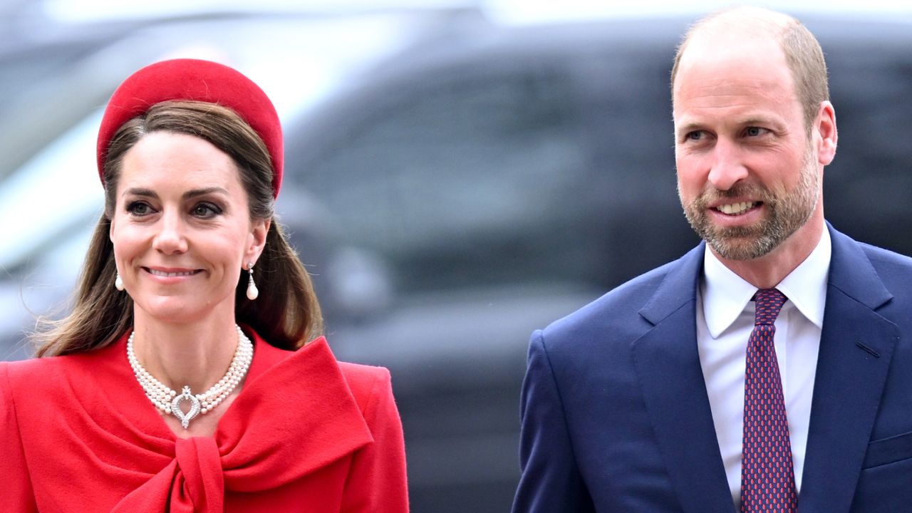 Kate Middleton wearing a red coat and headband walking next to Prince William wearing a blue suit on Commonwealth Day 2025