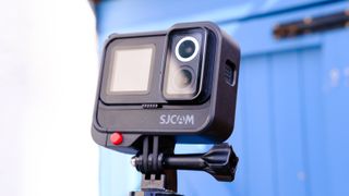 A photo of the SJCAM Sj20 being held up with the lenses showing against a blue backdrop.