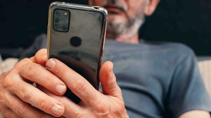 Photo of a man with a gray beard looking at his phone