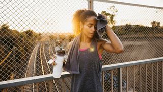 Woman toweling off sweat with a water bottle after run