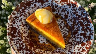 3/4 shot of a triangular slice of cornbread on a splotchy patterned plate