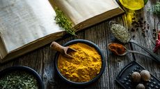 Turmeric on countertop with other spices and cookbook