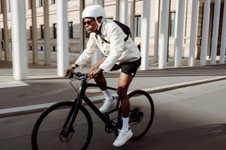 A rider cycling in a city on a Specialized Sirrus Carbon bike