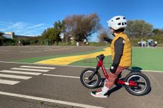 young boy sat on a red balance bike getting ready to race round a track designed specifically for kids