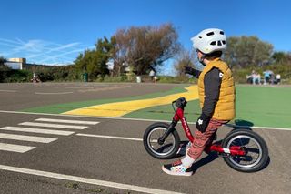 young boy sat on a red balance bike getting ready to race round a track designed specifically for kids