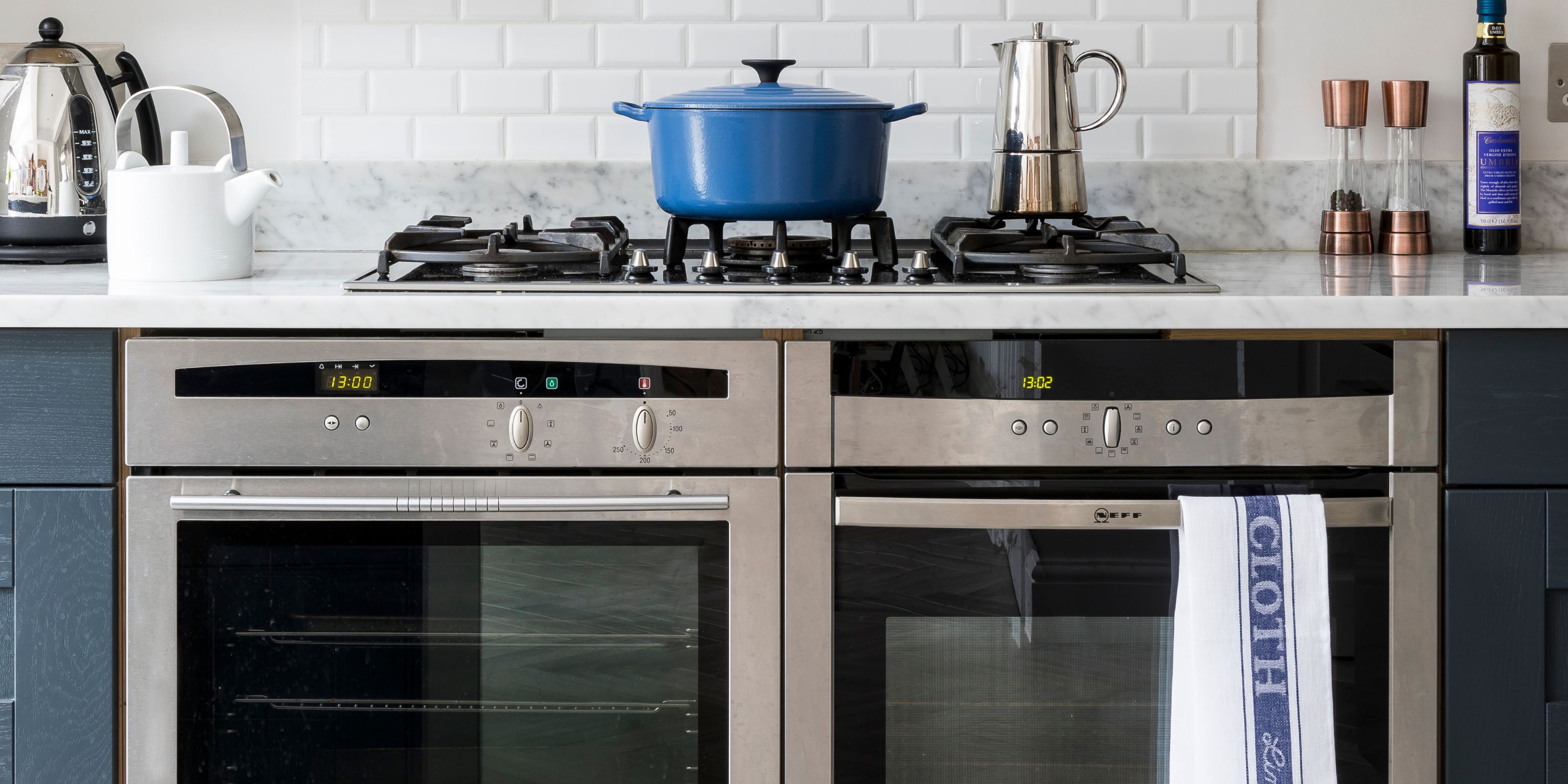 A double oven and gas cooker with a blue cast iron pot on top