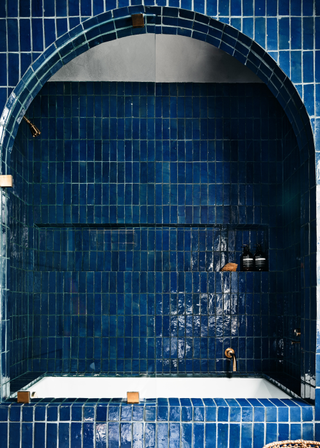 Blue zellige tiles in an arched built in bath.