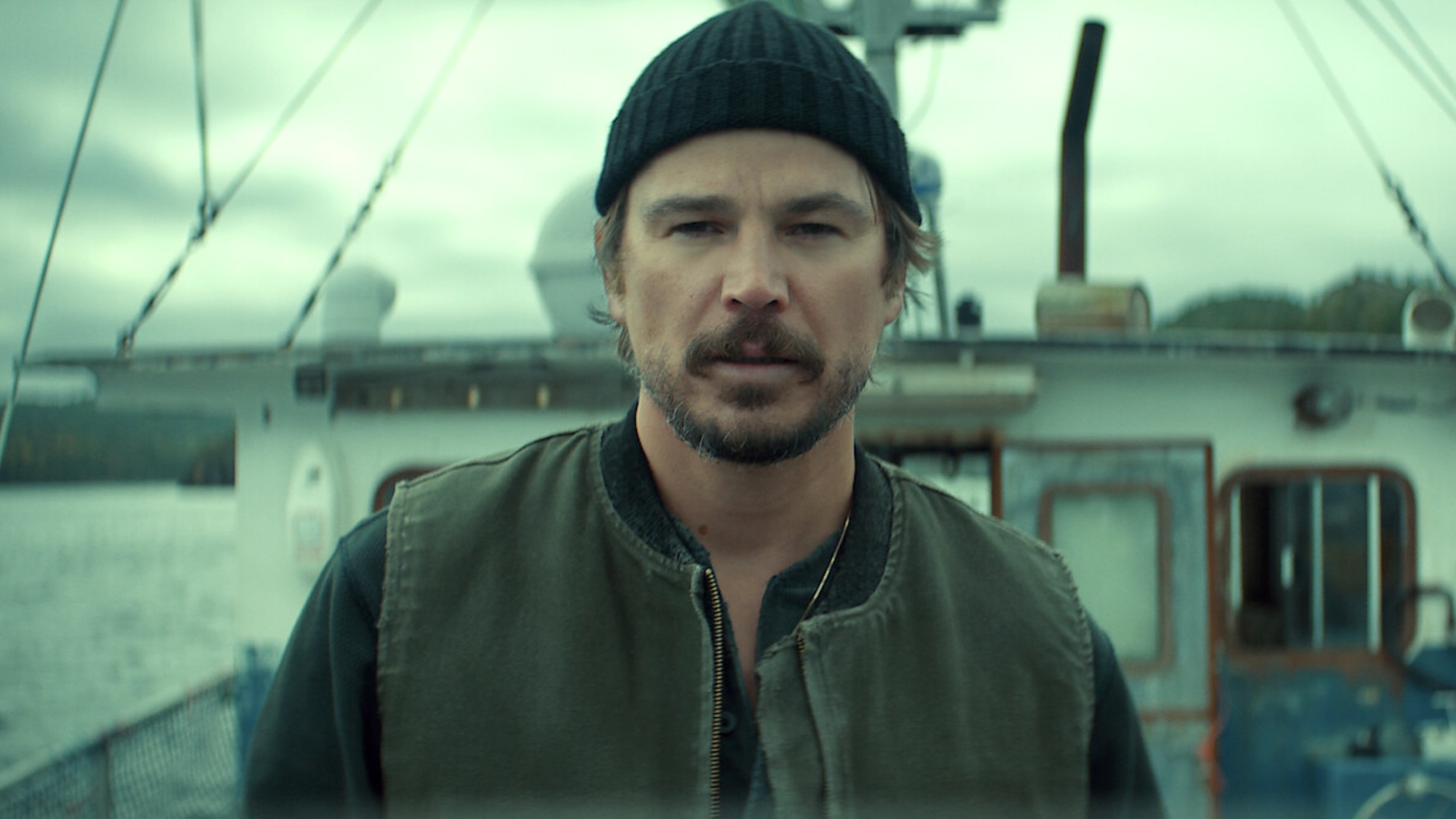 Josh Hartnett's Calvin Penney facing camera in jacket and knit cap, standing on a boat in Netflix's Below