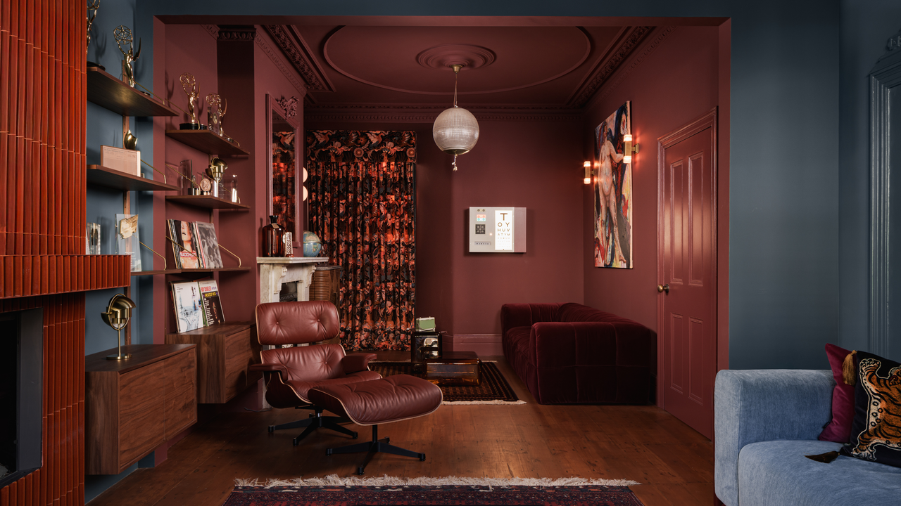 Living spaces zoned with color; one painted teal and the other a rust brown-red with a fireplace and a sofa in each space