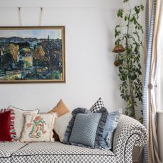 A living room with a patterned sofa and a painting hanging above it on a picture rail