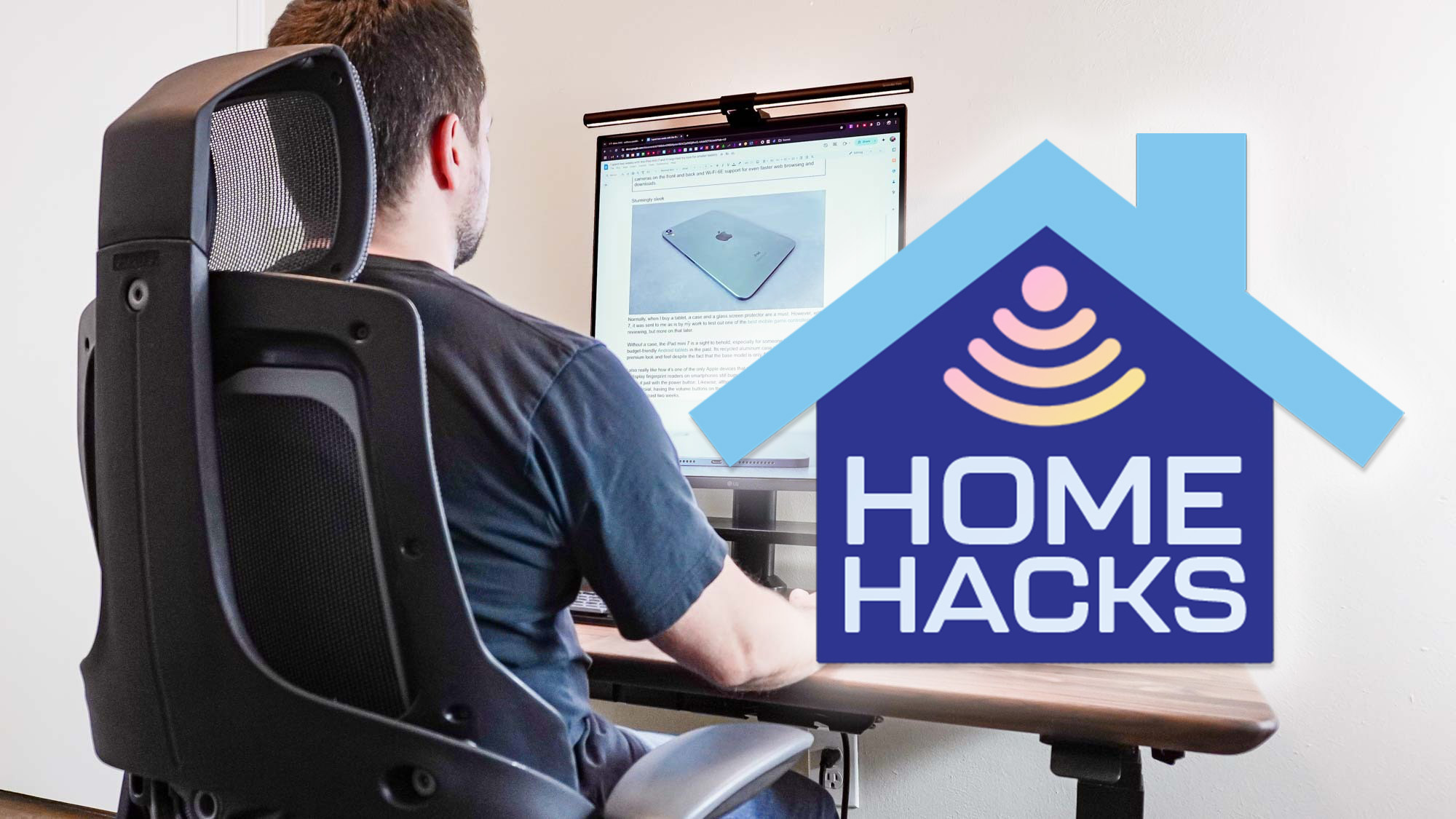 A person sitting at a carefully curated desk setup with a Home Hacks badge off to the side