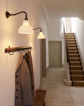 Wall lights by Davey Lighting York in hallway with coat hanger, men's jacket and stairs with runner decor