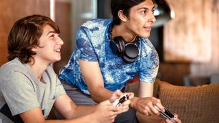 Two boys sitting on a couch playing a console game
