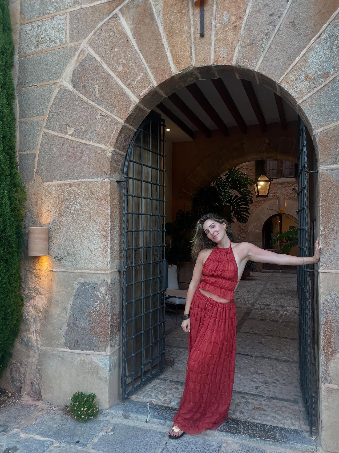 Fashion editor Anna Laplaca wears a Arcina Ori matching set and metal detailed sandals. She is stood in front of a stone walkway in a recent image from her Instagram.