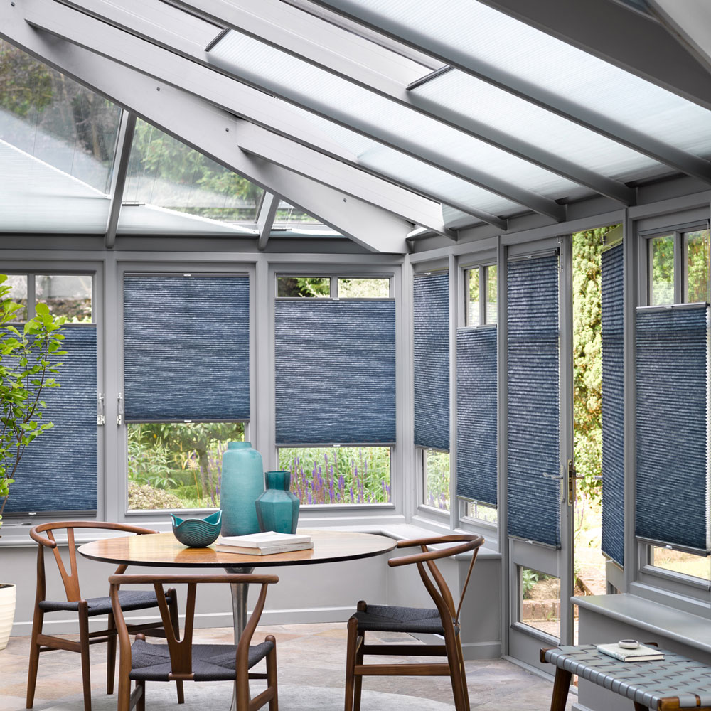 A conservatory with blue blinds and a wooden dining table