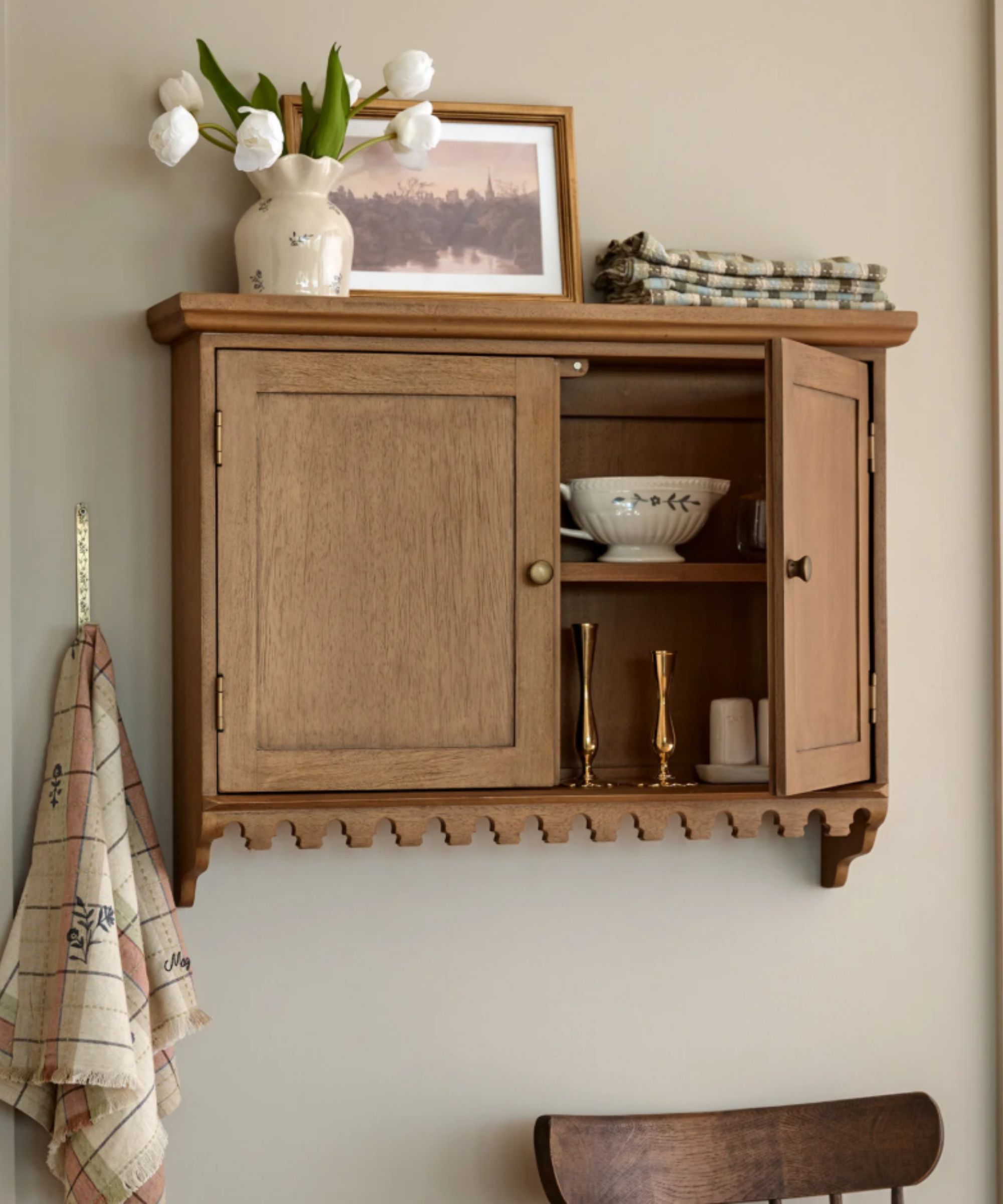 A wooden wall cabinet with scallop edge detail