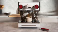 Victorinox x La Marzocco coffee tool sitting beside a white espresso maker in a white kitchen