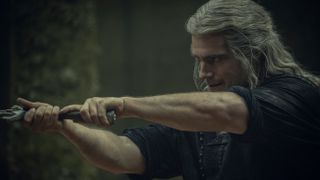 Geralt (Henry Cavill) seen from the side looking left brandishing a sword in The Witcher season 3