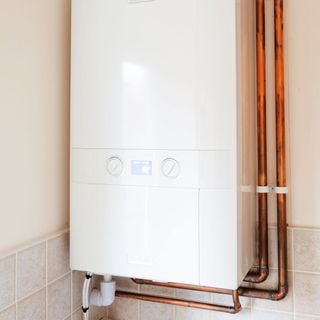 white boiler on white wall with copper pipes