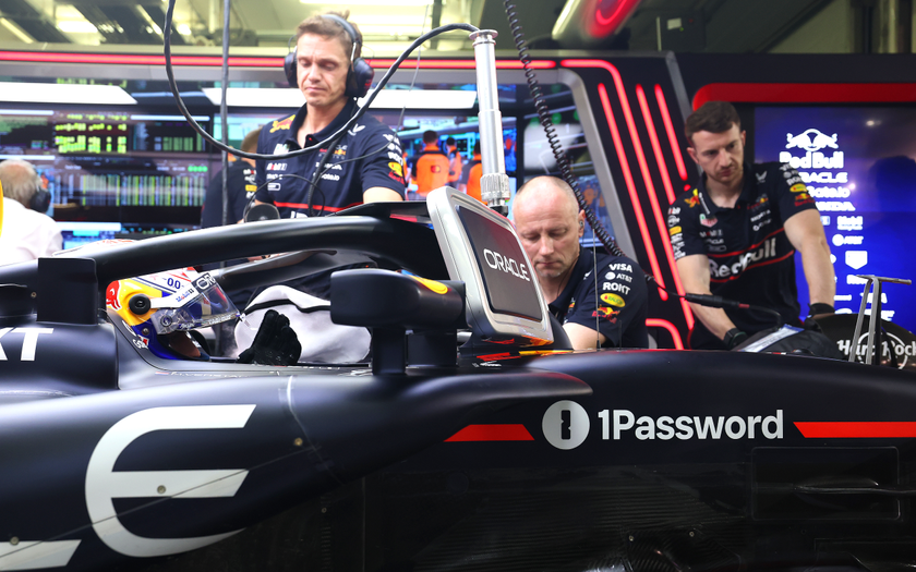A side shot of engineers working on an Oracle Red Bull Racing Formula 1 car with the 1Password logo visible on the side.
