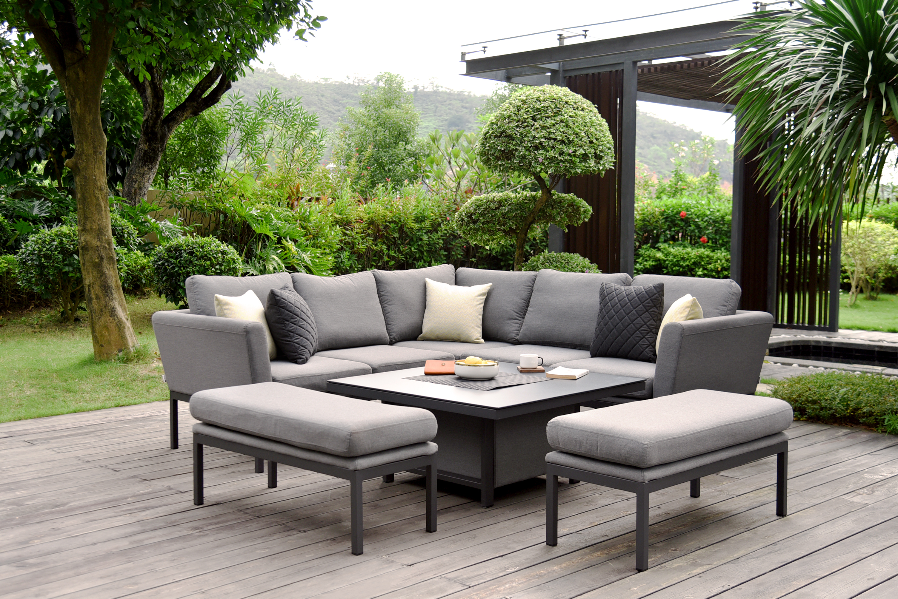 A backyard decking area with grey outdoor seating below a canopy