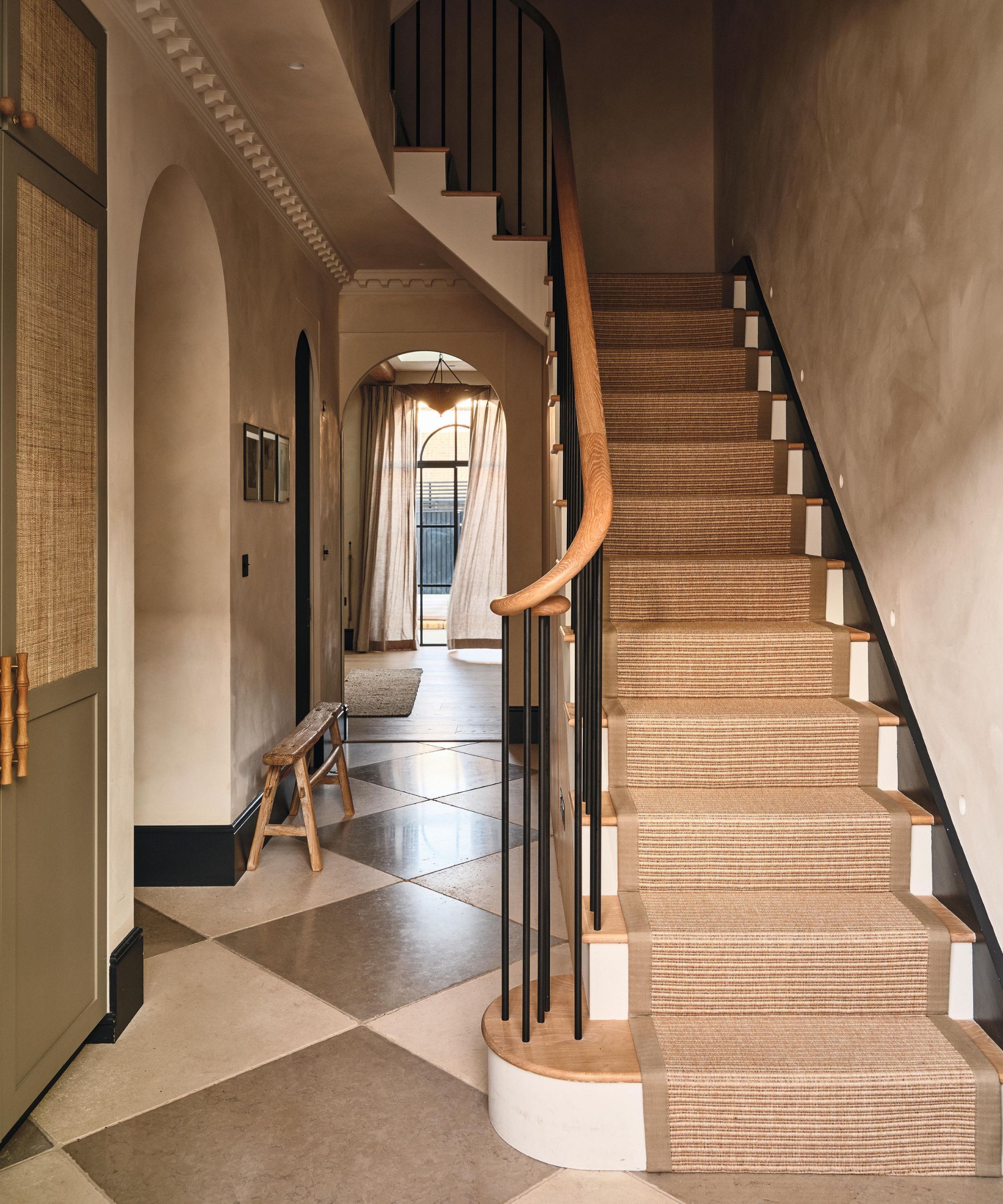 a london entryway with tiled checkerboard floors, white oak and black metal staircase with limewashed walls