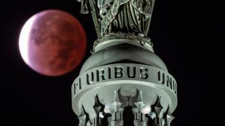 The nearly perfectly eclipsed 'beaver moon' in November 2021 seen behind the Statue of Freedom at the top of the tome on Capitol Hill in Washington DC.
