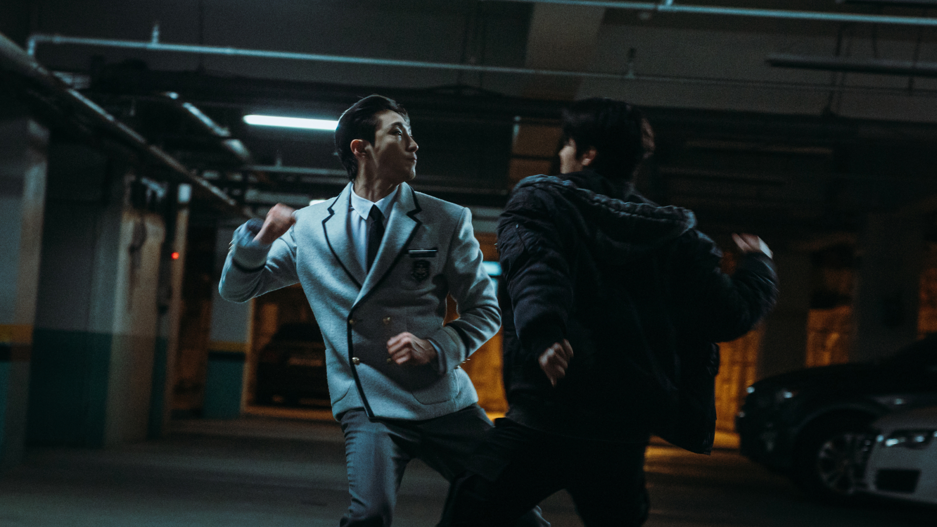 Two men (Bae Na-ra as Na Baekjin, Ryeo Un as Park Humin) fight in a parking garage in Weak Hero Class 2