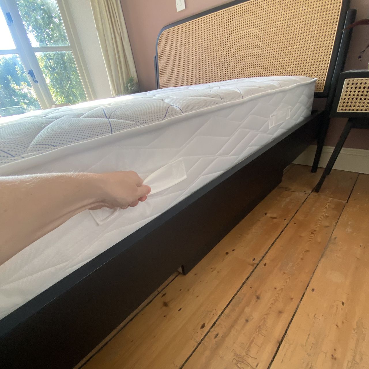 A hand holding the white handle on the side of the Bensons for Beds Simply Support Pocket Sprung Mattress.