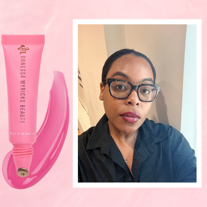 A woman wearing a black button up with pink glossy lips. She is next to a tube of lip gloss.