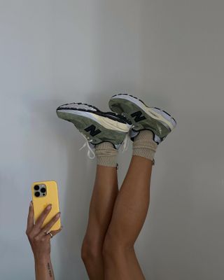 Woman taking a picture of her shoes with her legs up in the air.