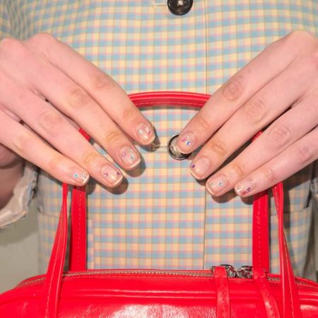 An image of natural nails with colorful gemstones.