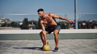 Man outdoors training holding a kettlebell in right hand 