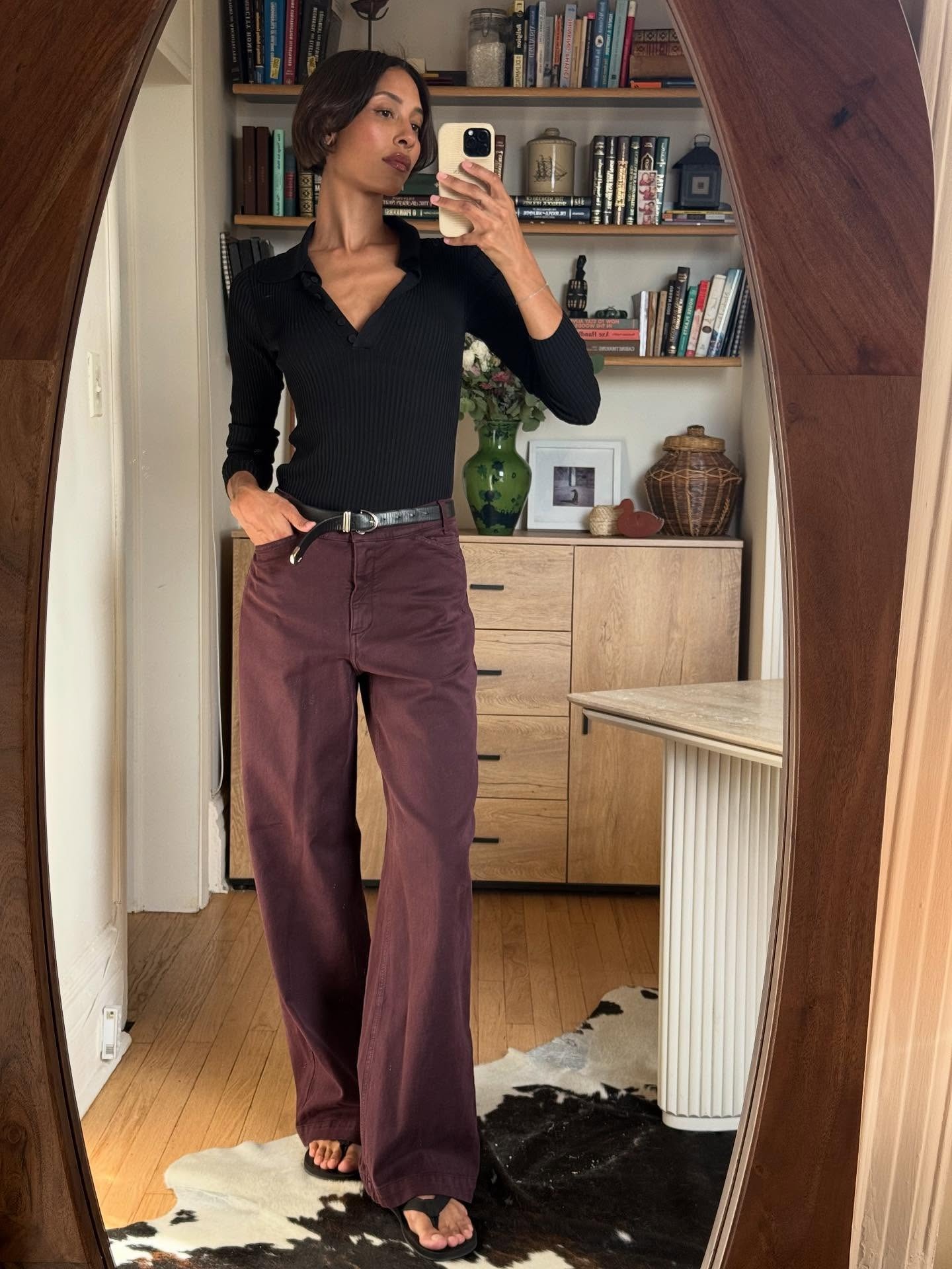 Influencer @tylynn wears a black top with burgundy jeans and black sandals.