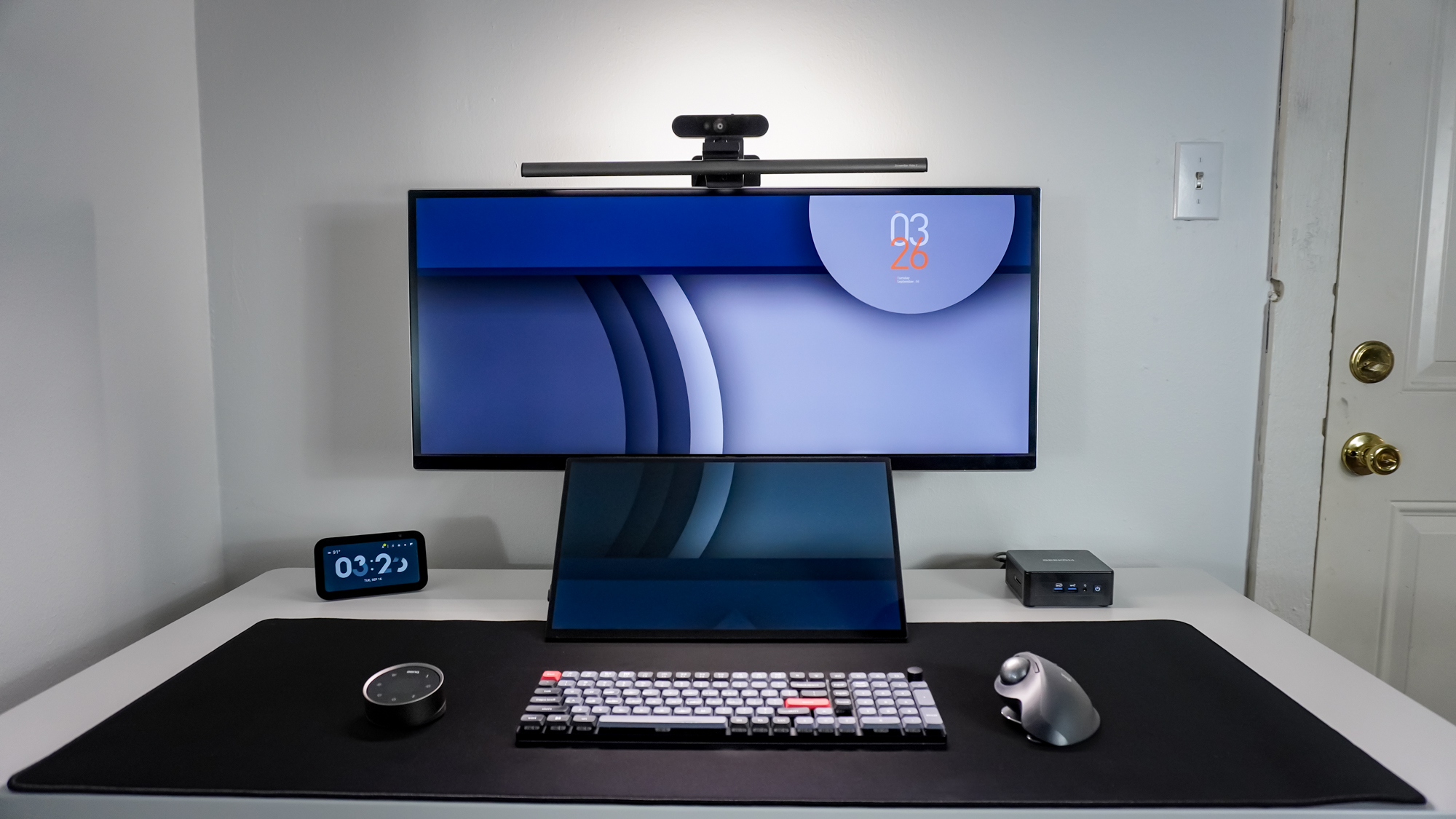 A desk setup built around the Hexcal Elevate standing desk with a BenQ ScreenBar Halo 2 on top of an ultrawide monitor