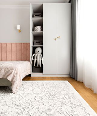 A young girls bedroom with a soft octopus toy and a large white floral area rug
