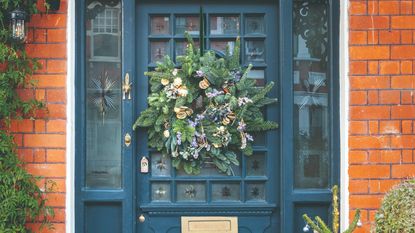 A blue front door decorated with a Christmas wreath