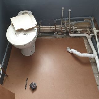 bathroom with broken walls and pipeline with measurement tape and pen