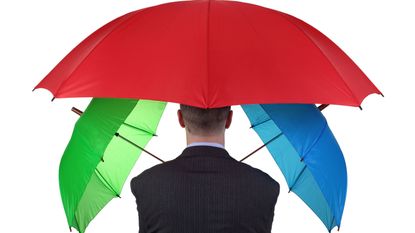 A man holds three umbrellas, his back to the camera.