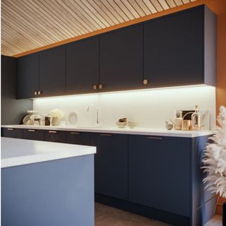 white worktops with blue kitchen island and cabinets with under cabinet lighting